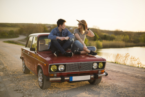 Two people sitting on the hood of a car