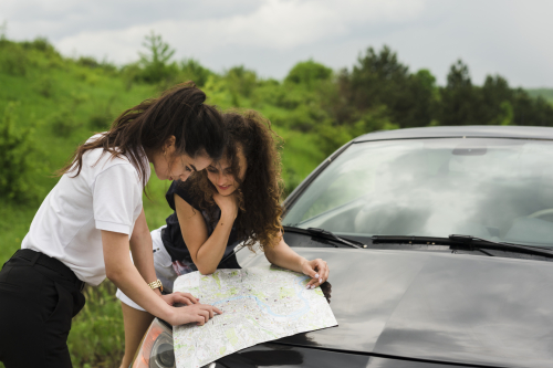People looking at a map on the hood of their car