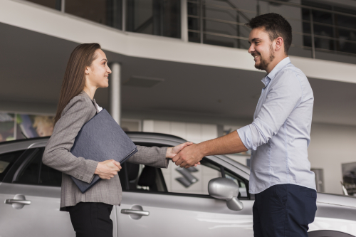 People shaking hands in a car dealership