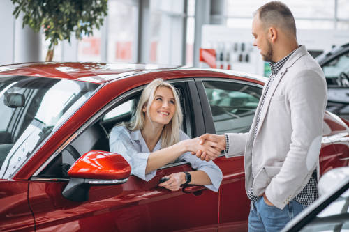 People shaking hands at a car dealership