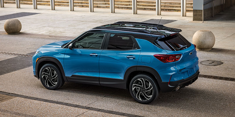 A blue Chevrolet SUV parked on a modern paved area with large round stones.