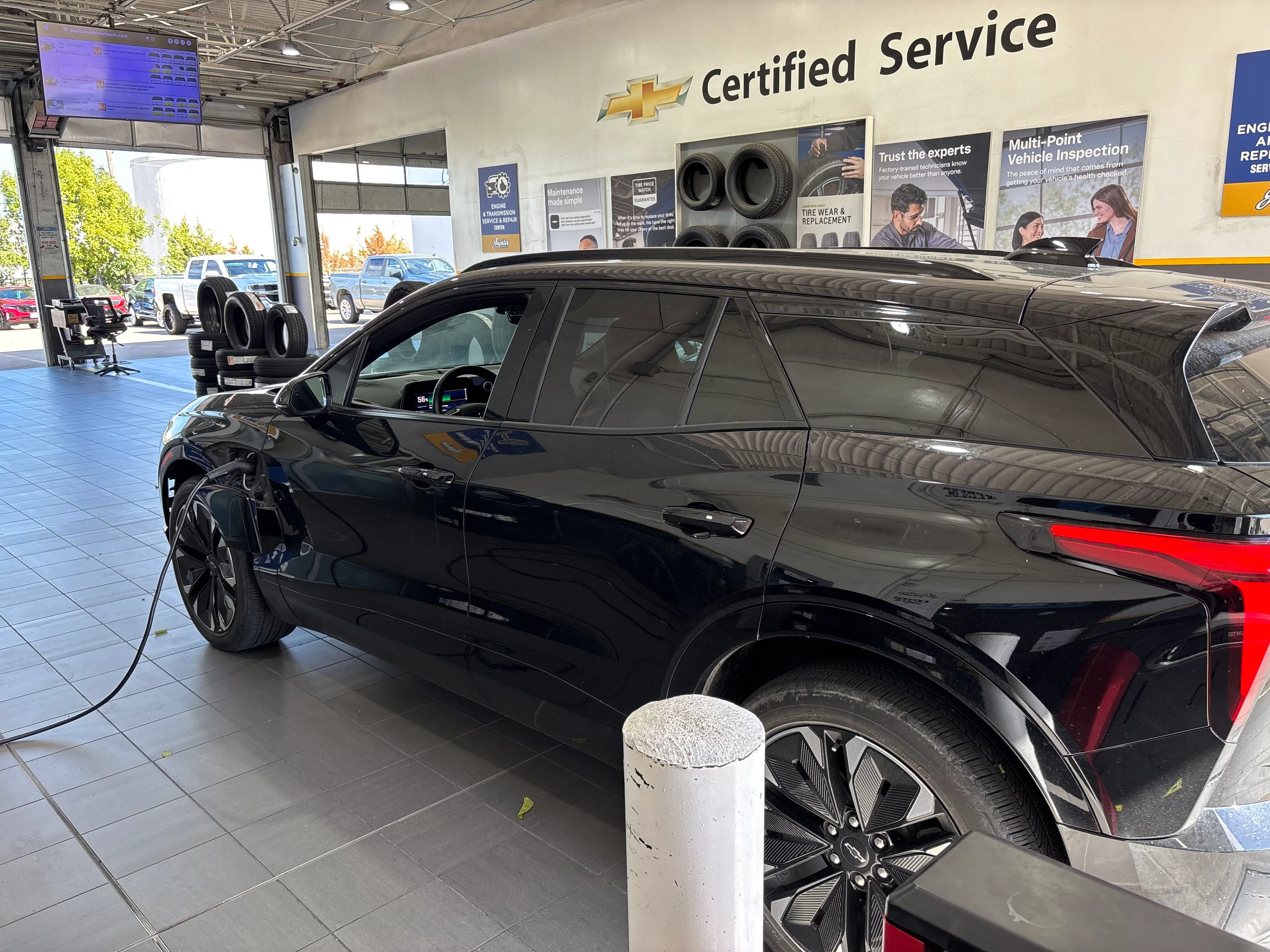 Black Chevrolet Blazer EV plugged in to charge inside the Chevy Certified Service bay at Jupiter Chevrolet in Garland, TX