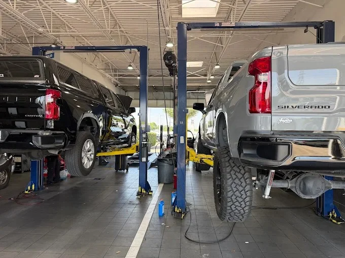 Two Chevrolet Silverado trucks on lifts in the Jupiter Chevrolet service department in Garland, Texas