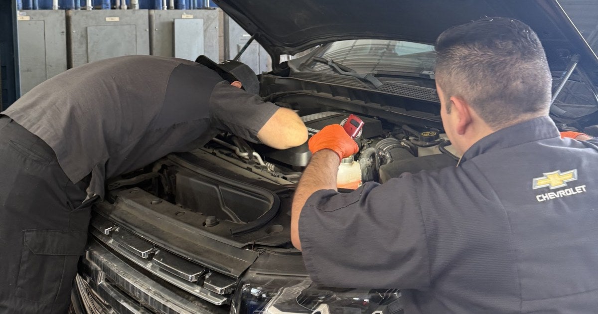 Two Jupiter Chevrolet technicians inspecting the engine bay of a Chevrolet during a service visit in Garland, TX